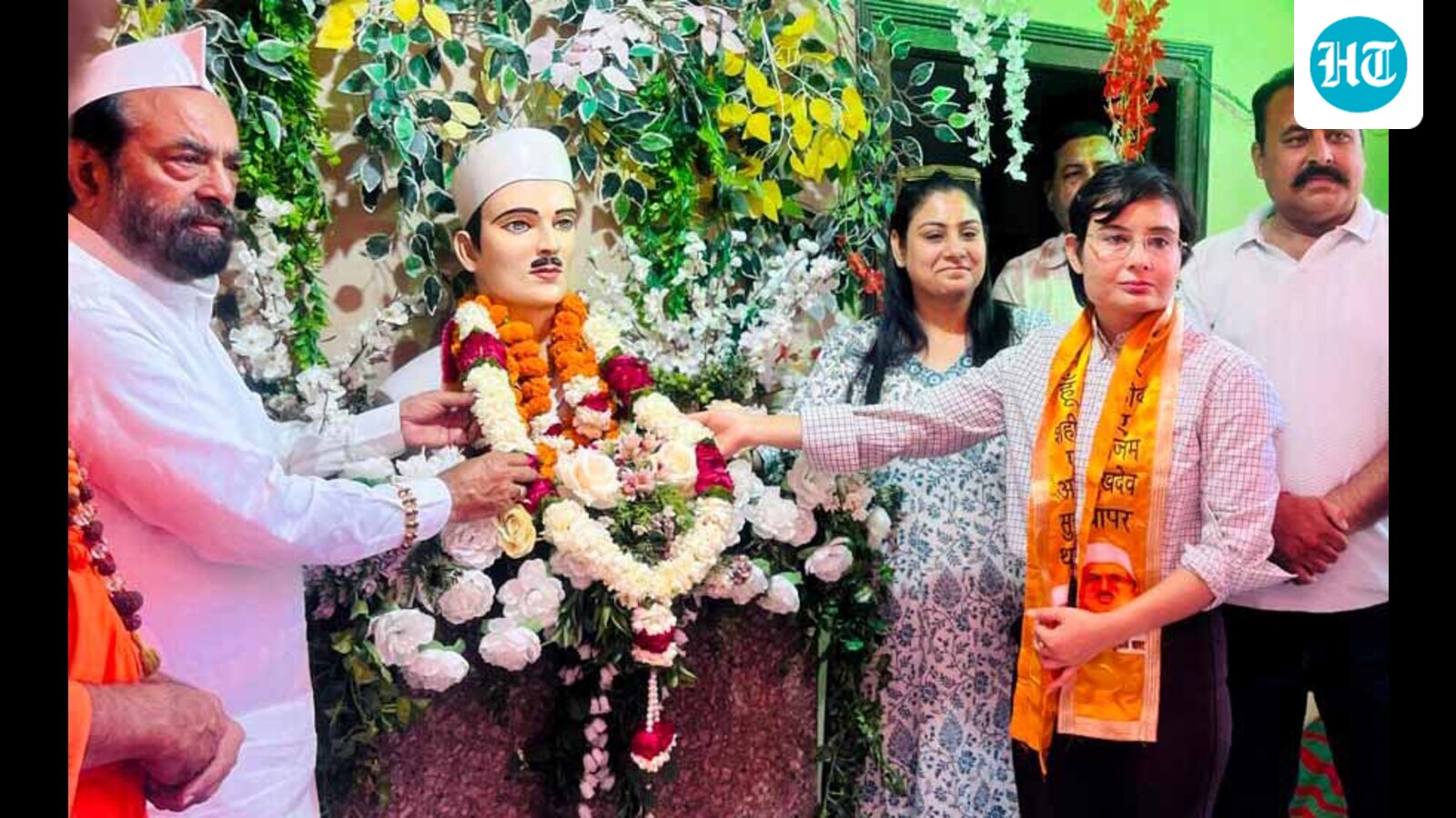 People placing floral garlands on a statue of Sukhdev Thapar during a commemoration
